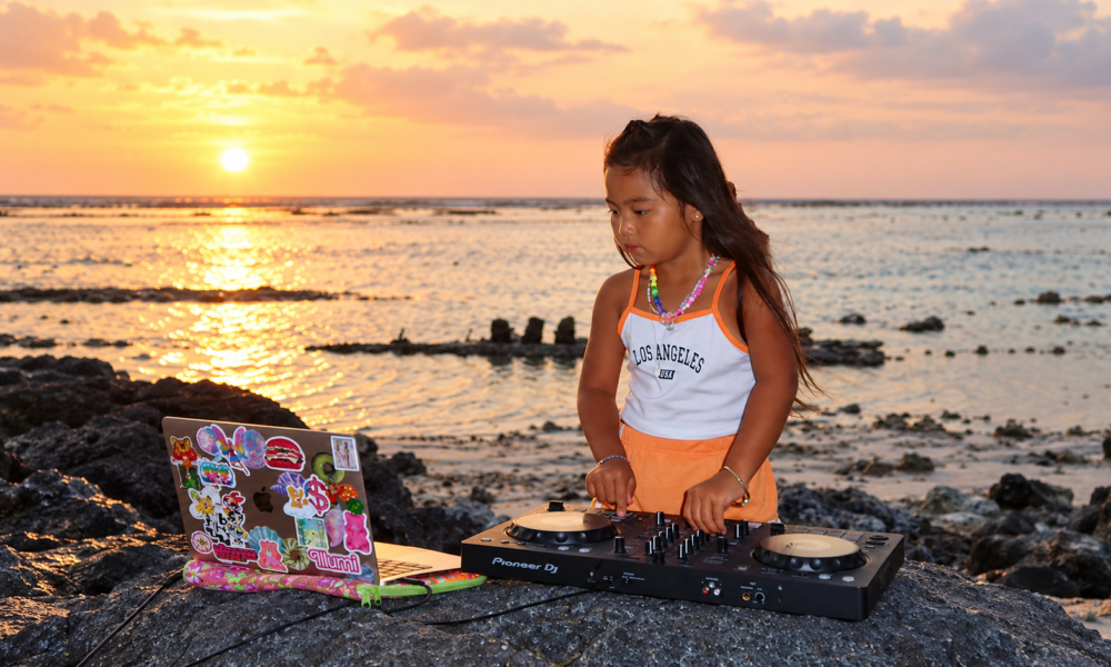 DJ ILLU using a Pioneer DJ controller beside the ocean at sunset