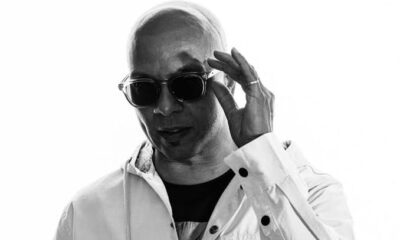 Black-and-white portrait of American house music DJ and producer Cevin Fisher wearing sunglasses and a white jacket.