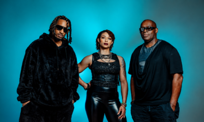 Dantiez Saunderson, Steffanie Christi’an and Kevin Saunderson posing together against a blue studio background