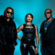 Dantiez Saunderson, Steffanie Christi’an and Kevin Saunderson posing together against a blue studio background