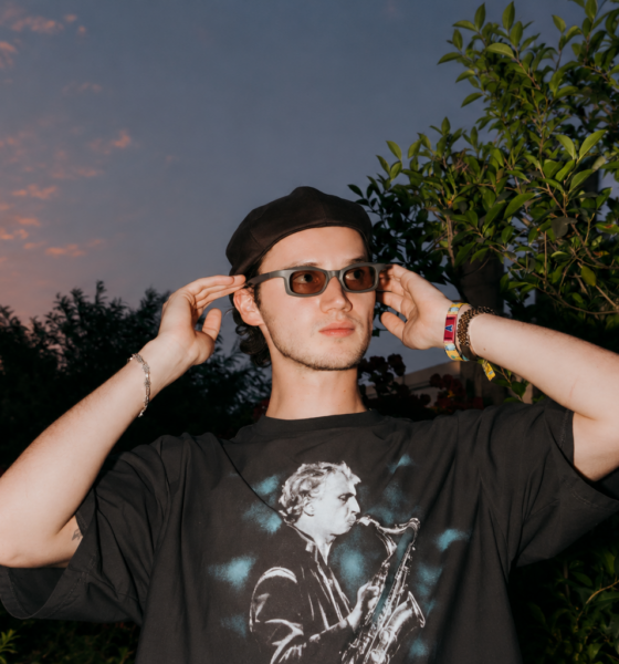 Mau P wearing sunglasses and a black cap outdoors at sunset