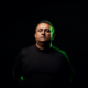 Midnight Evolution wearing a black shirt against a dark background for his new single Meridian on Interplay Flow