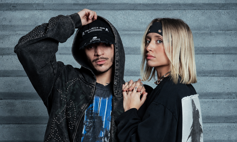 Nico Moreno and Novah posing together in black outfits against a concrete wall