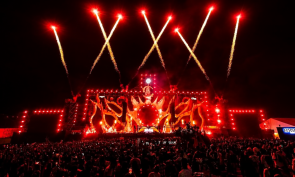 Sunburn Festival stage glowing red as fireworks launch above a large nighttime crowd.